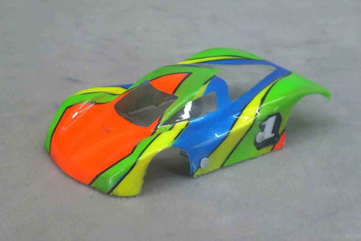 Front three-quarter view of Vector Strike painted Lexan HO slot car body with orange nose, green and blue panels and yellow stripes outlined in black