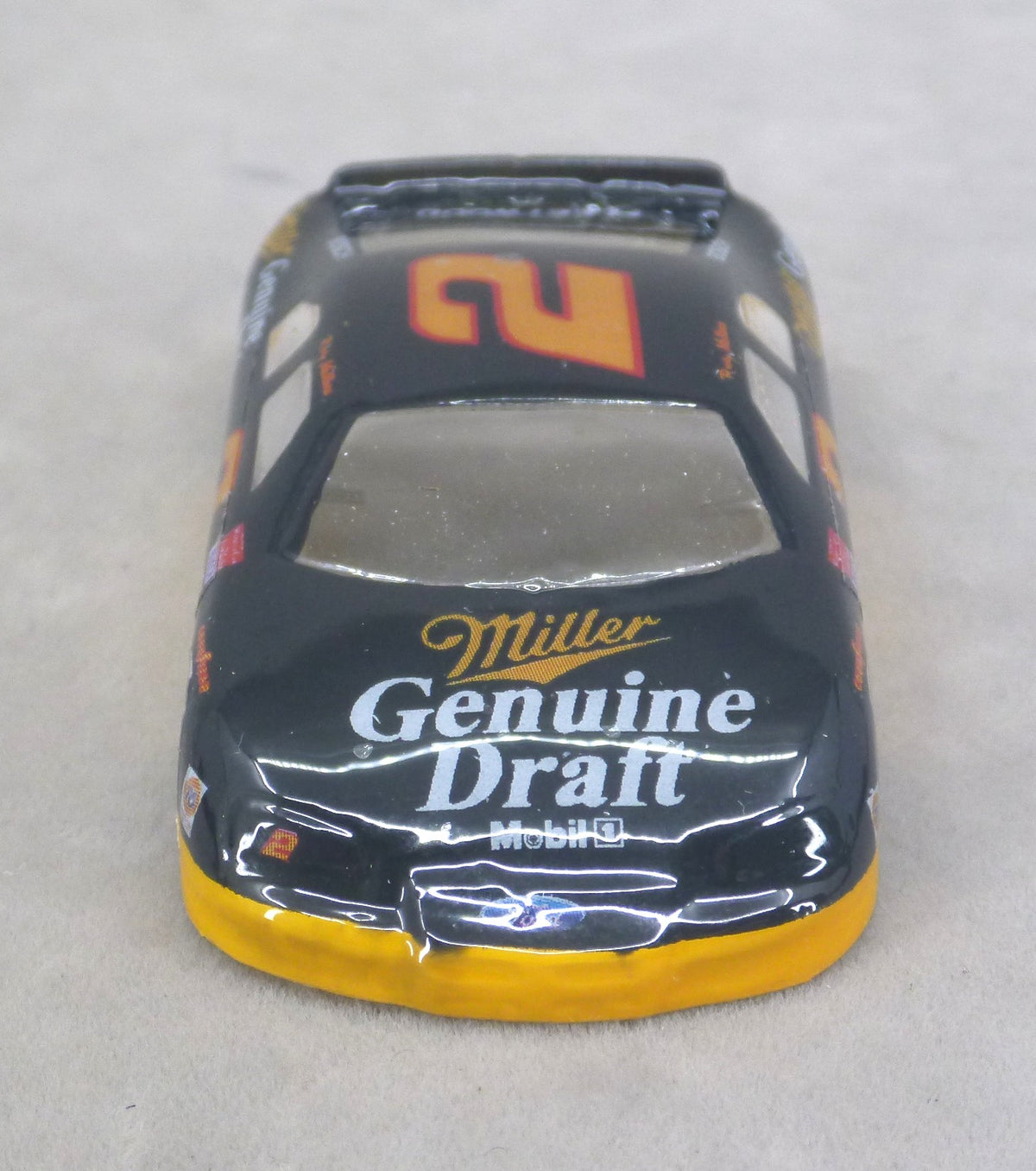 A lexan race car modeled after a Miller Genuine Draft / Mobil 1 driver car, featuring a black body with a large orange number 2 on the roof and sponsor logos on the hood and sides.