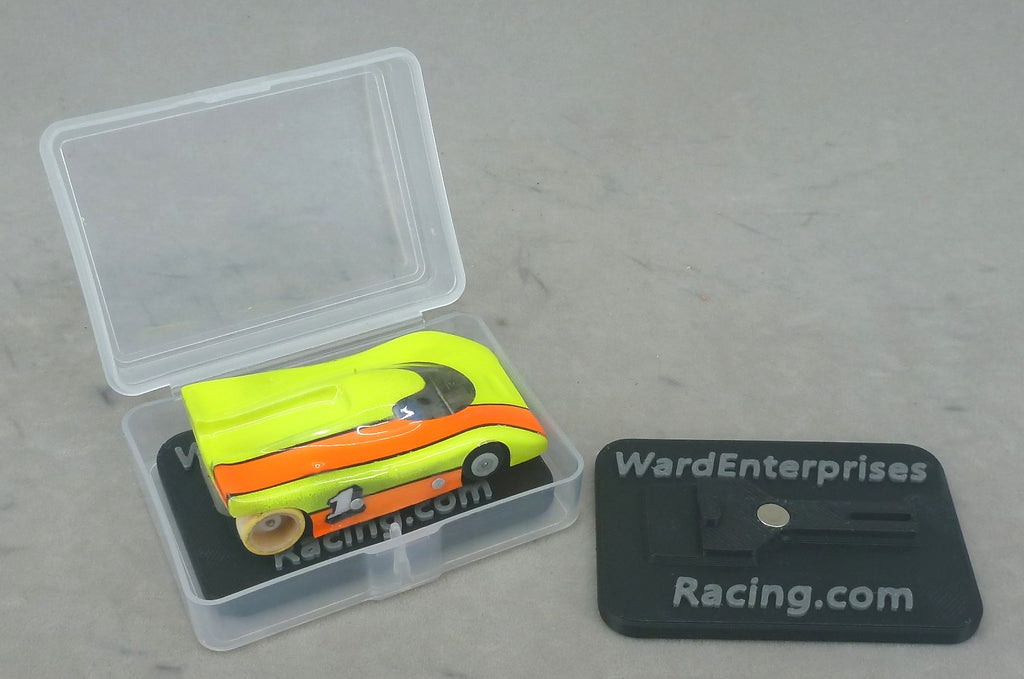 Clear HO slot car case with painted G Chassis car on a black chassis stand, spare stand beside