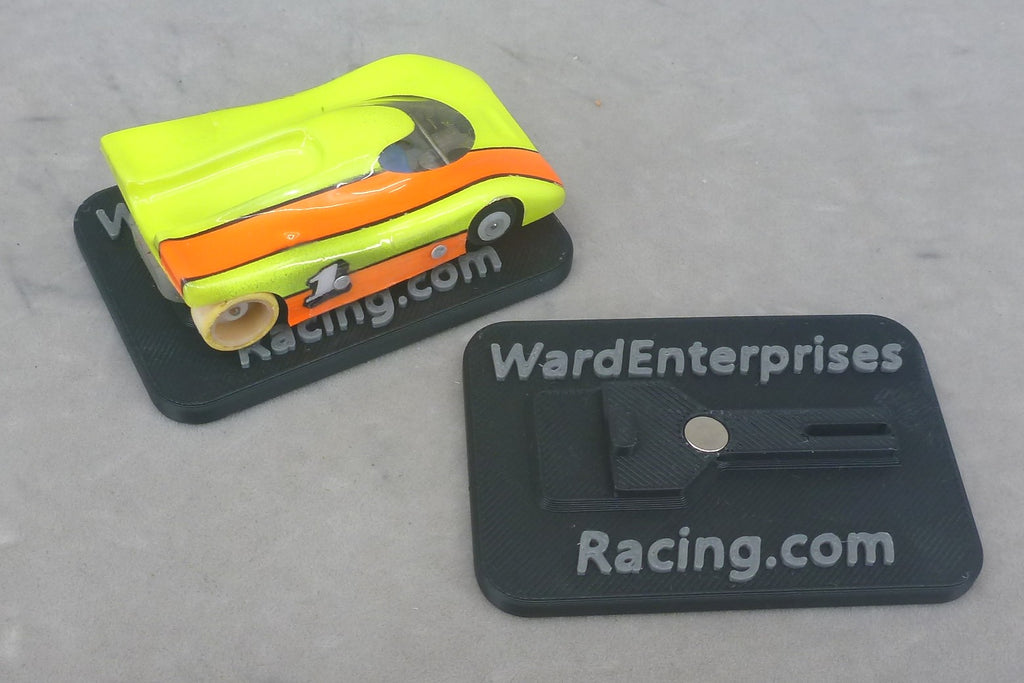 Painted G Chassis HO slot car resting on a magnetic chassis stand with Ward Enterprises Racing branding