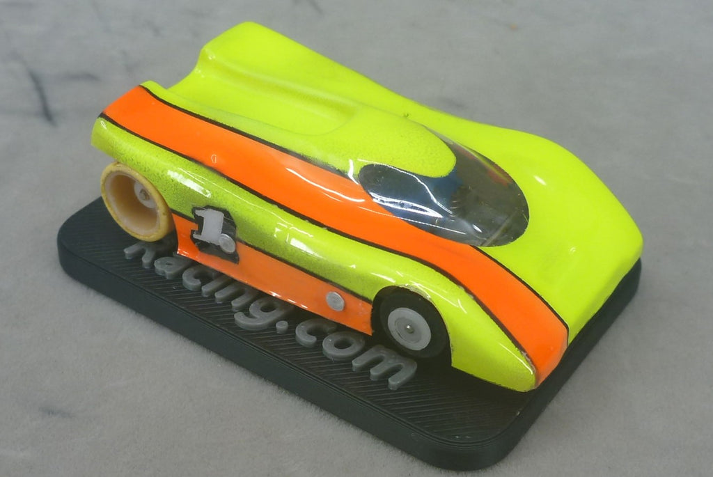 Close-up of a painted yellow and orange G Chassis HO slot car on a black chassis stand