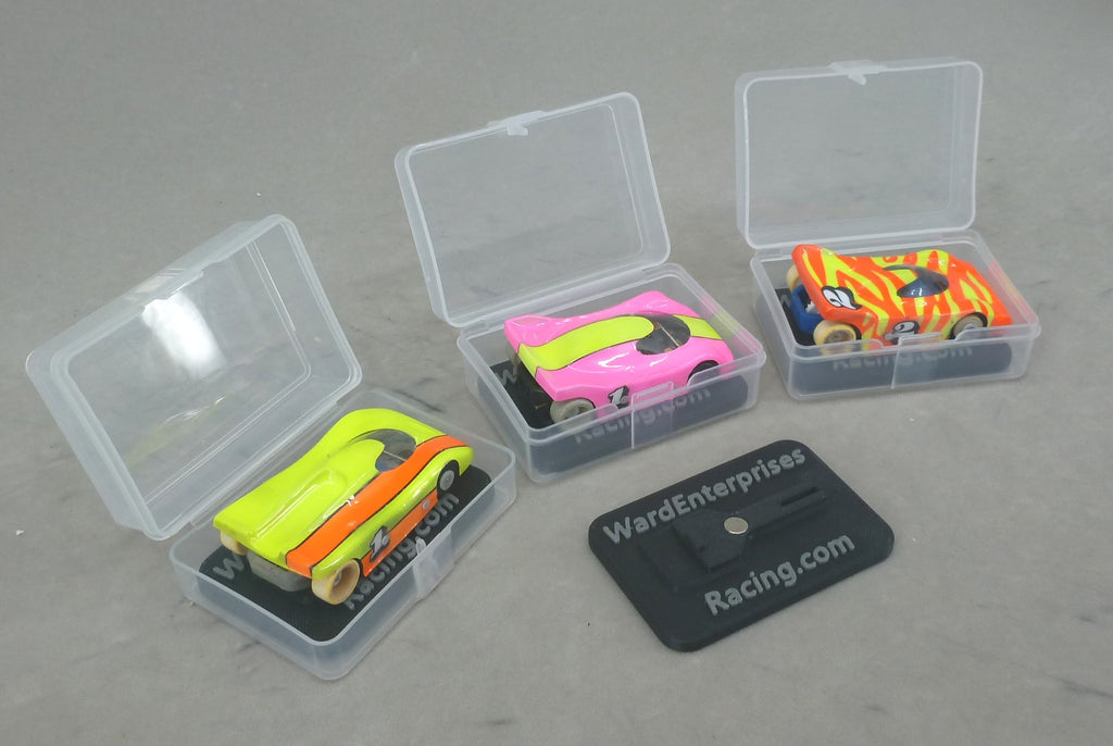 Three clear HO slot car cases with painted G Chassis cars on black chassis stands
